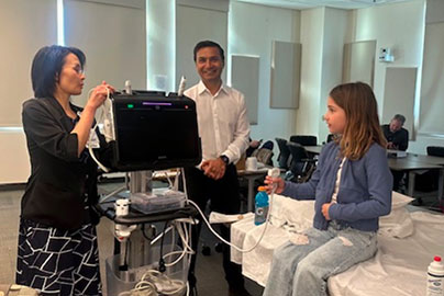 Ultrasound demonstration with two doctors, and patient in hospital bed next to monitor