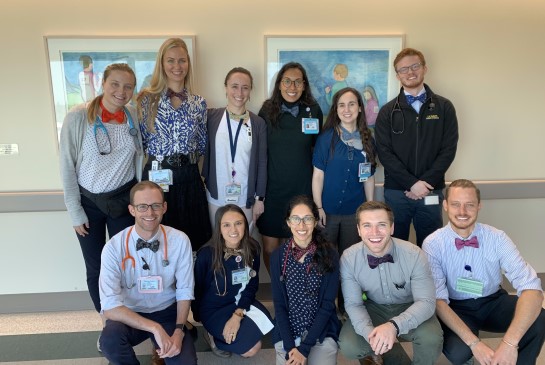 Eleven residents pose for photo with bow ties on in hospital hallway.