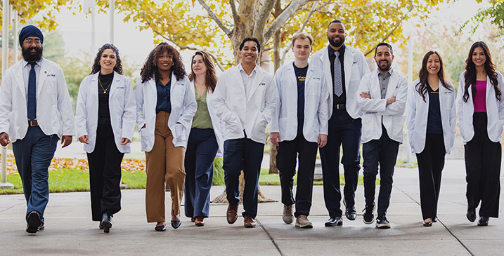 Diverse group of students line up and smile in UC Davis shirts