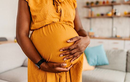Pregnant women wearing bright orange dress in large living room. 
