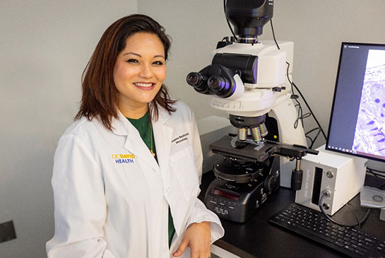 Drs. Bautista in lab sitting by large microscope and computer