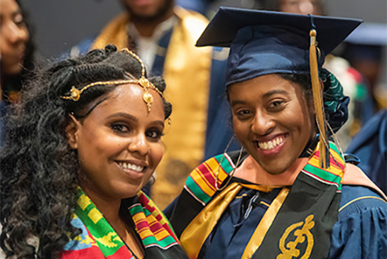 Two students wearning graduation gowns and stoles