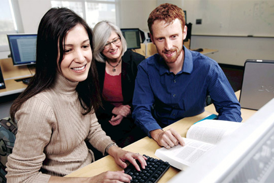 Three researchers sitting at desk and looking at computer monitor