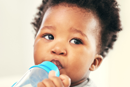 Close up of a small child drinking from a plastic bottle.