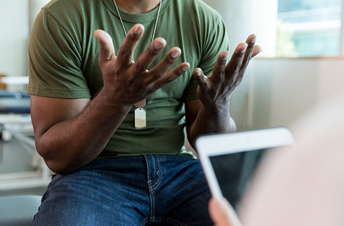 A man in a clinic setting talking to a therapist