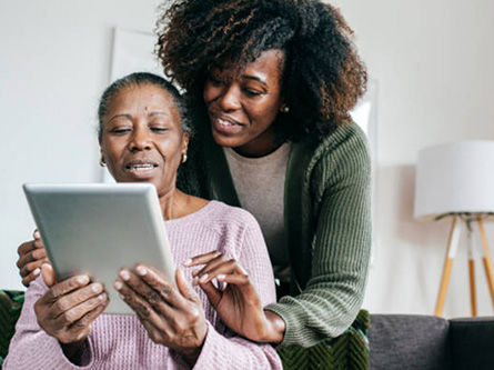 daughter helping elderly mother use tablet