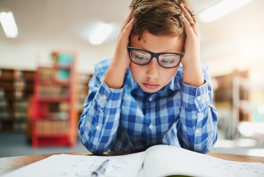 A boy sits with his head in his hands