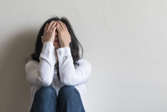 Woman sitting with head in hands looking distressed
