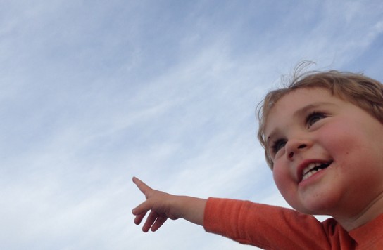 A young child pointing to the sky