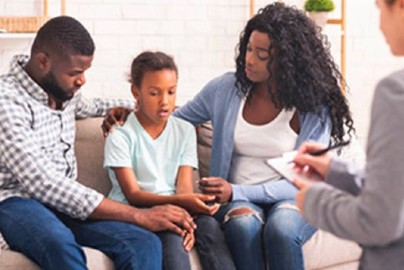 A girl sitting with her parents and therapist