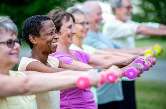 A group of older adults holding hand weights in a workout class