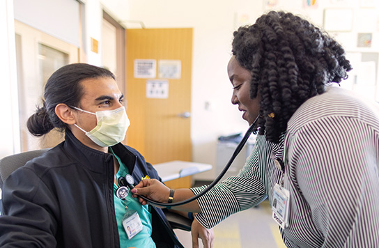 A resident using a stethoscope on another resident