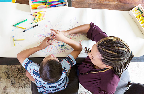 Young boy and woman coloring at a table