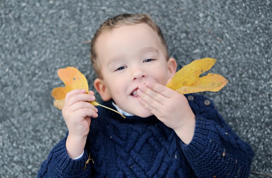 A young child playing with leaves