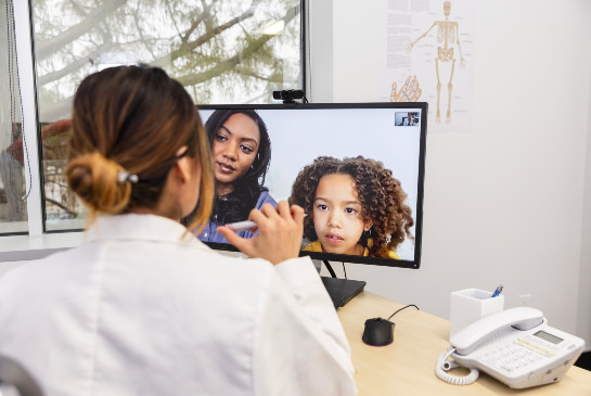 A practitioner speaking to a child and parent in a virtual meeting
