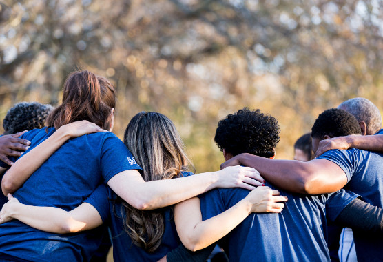Diverse group of students with arms around eachothers shoulders