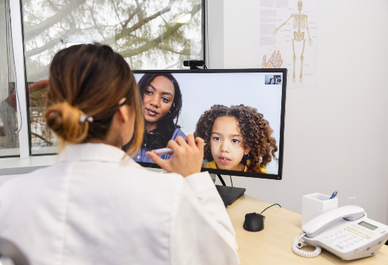 A child and parent talking to a clinician via telehealth visit