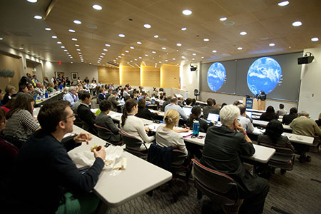 Health Quality Forum, large confernece room, theater style with desks, two large screens with photo of earth on screens