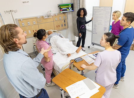 A group of health care workers in a simulated hospital room.