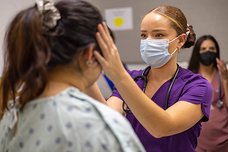 A nurse is working with a person acting as a standardized patient. 