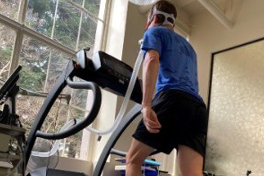 A man walking on a treadmill with a VO2max mask.
