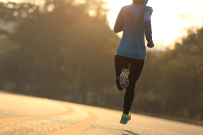 Person running down the road towards sunset.