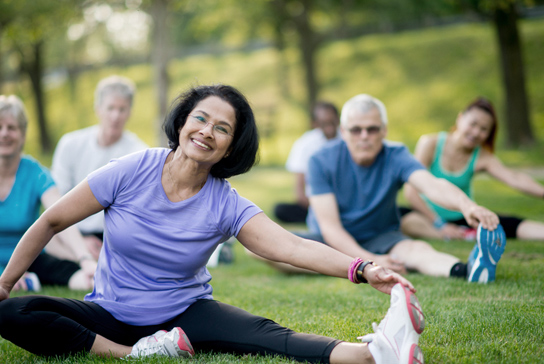 Group of people on green grass stretching.