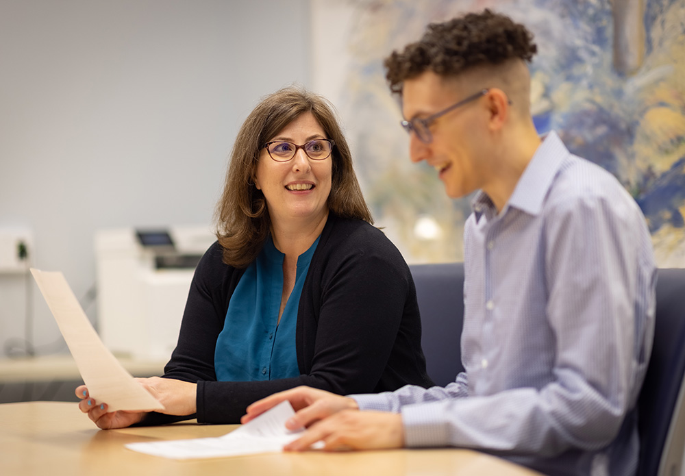 Robin Whitney, left, meets with staff member Benjamin Link in a conference room