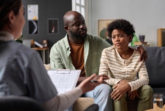 Stock image of a father and son talking to a therapist