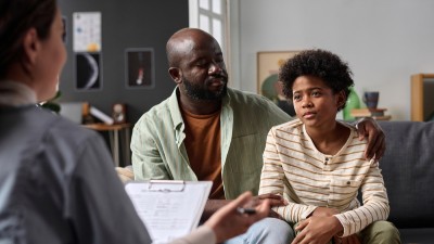 Stock image of a father and son talking to a therapist