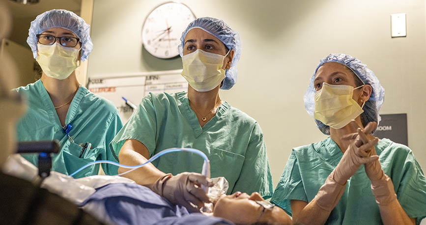 three doctors wearing masks and scrubs staff with patient