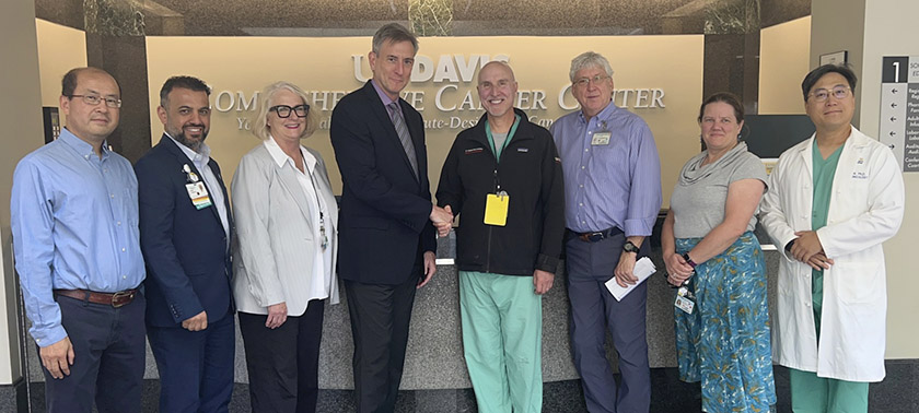 Group of six men and two women in front of main reception at the cancer center