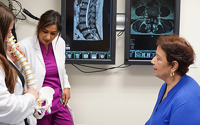 woman with advanced practice providers looking at a spine model