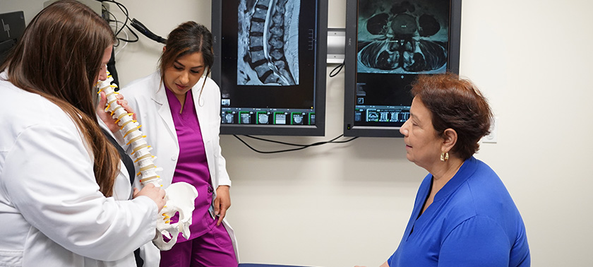 Woman with Advanced Practice Providers learning looking at a spine model