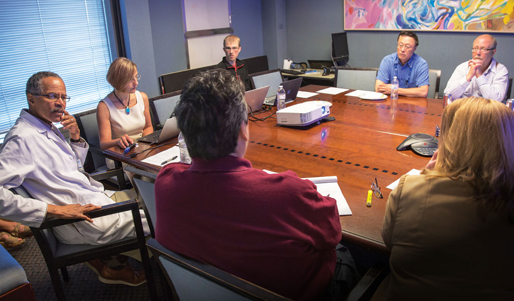 A lunchtime meeting of the “Brain Innovation Group” includes clinical and research faculty from left, James Boggan, Laura Marcu, Brad Hartle (biomedical engineering graduate student), Jian-Jian Li and Robert O’Donnell. Not pictured, Ruben Fragoso. Staff (not facing camera) include Edson Kong and Karol Kyte.