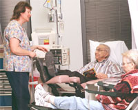 PHOTO — Nurse Anne Beatie checks in on retired engineer Frank Tate, a lung cancer patient, and his wife Pamela.