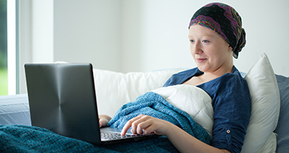 Cancer patient laying in bed on the computer