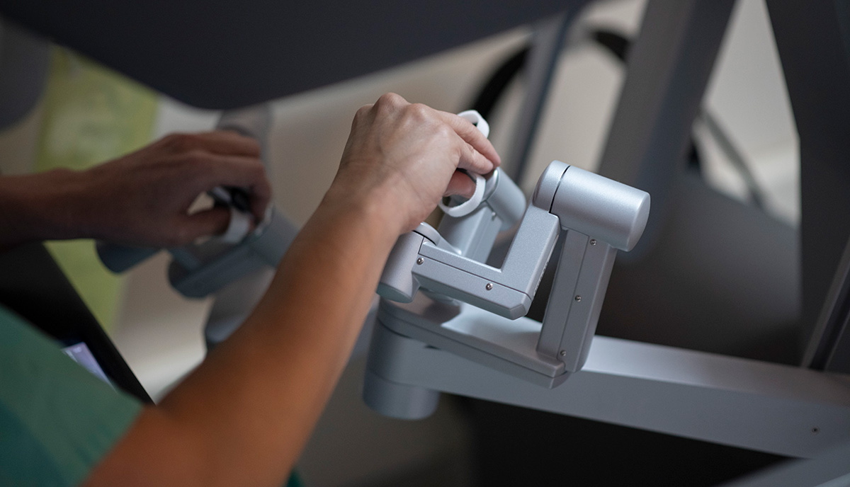 Person in green scrubs moving robotic arms