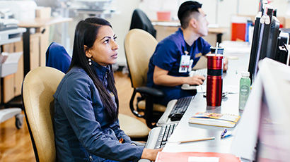 Male and female at a desk looking at their computer