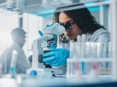 Researcher looking in a microscope (c) UC Regents. All rights reserved.